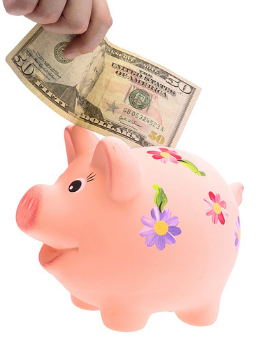 hand-putting-cash-in-piggy-bank