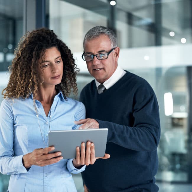 Shot of two businesspeople working late on a digital tablet in an office