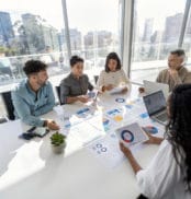 Group of people working with Paperwork on a board room table at a business presentation or seminar.