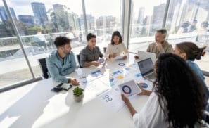 Group of people working with Paperwork on a board room table at a business presentation or seminar.