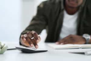 Shot of a young man using a calculator at work