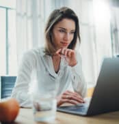 Confident businesswoman working on laptop at her workplace at modern office.Blurred background.
