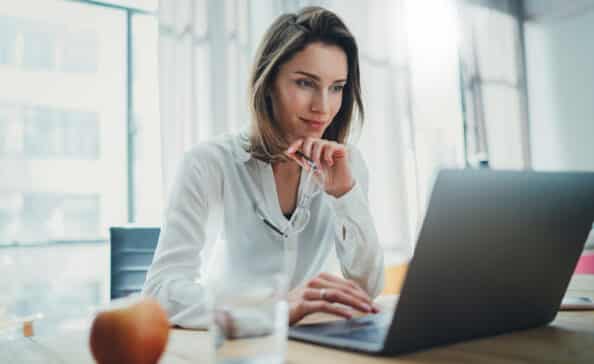 Confident businesswoman working on laptop at her workplace at modern office.Blurred background.